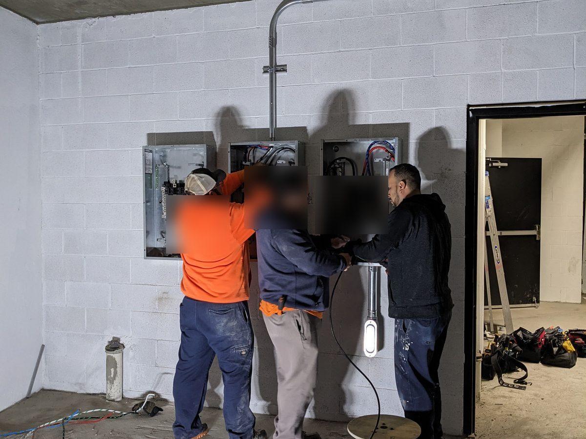 Three-man crew installing panels in commercial parking structure - AMY Electric