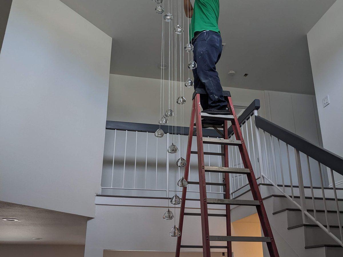 Dramatic chandelier installation on tall ladder - AMY Electric